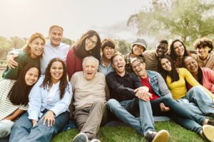 Diverses Team bestehend aus Männern und Frauen aus unterschiedlichen Altersklassen und mit verschiedener Herkunft sitzt in Park zusammen