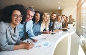 Gruppe von diversen Mitarbeitern posieren lächelnd für Unternehmensfoto