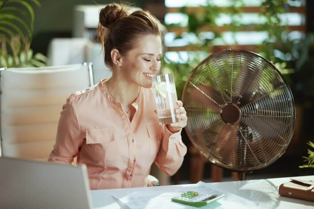 Lächelnde Frau trinkt Wasser im Büro