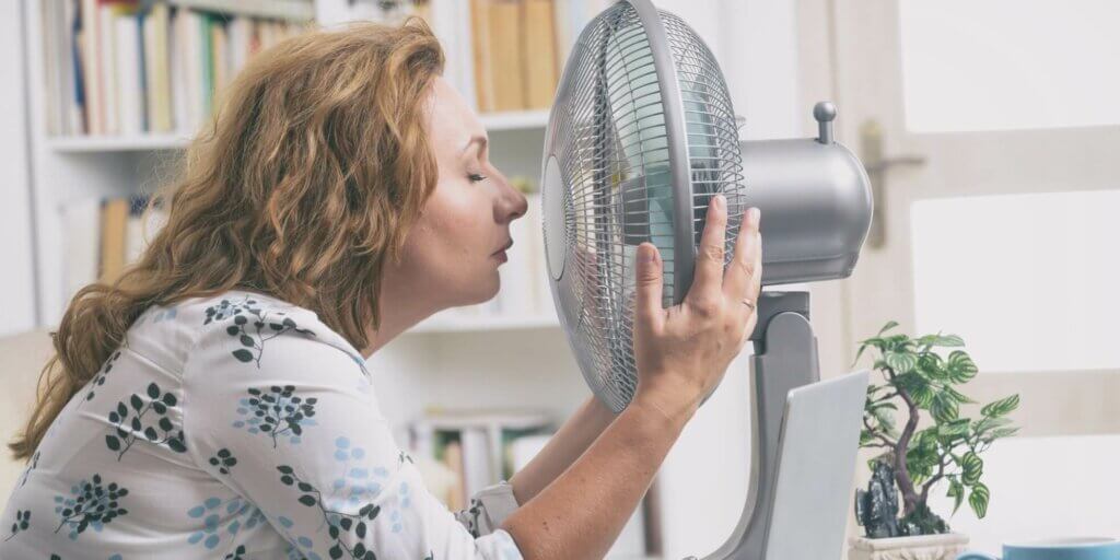 Hitzefrei im Büro-Frau nah am Ventilator