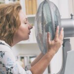 Hitzefrei im Büro-Frau nah am Ventilator