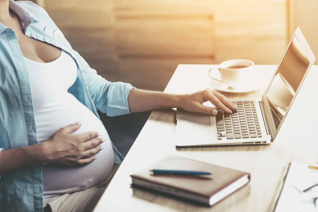 Schwangere sitz am Laptop und arbeitet