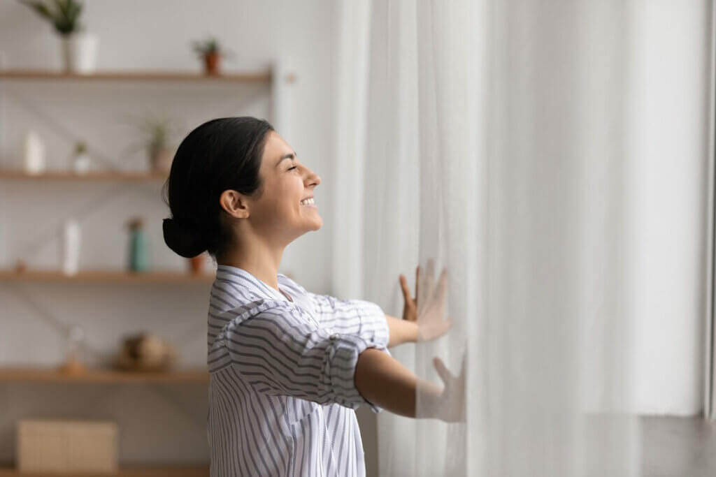 Frau öffnet lächelnd das Fenster