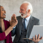 Frau und Mann aus zwei verschiedenen Generationen geben sich High Five am Arbeitsplatz