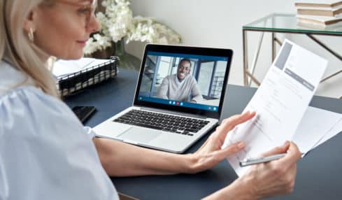 Personalerin liest CV während Videocalls mit Bewerber