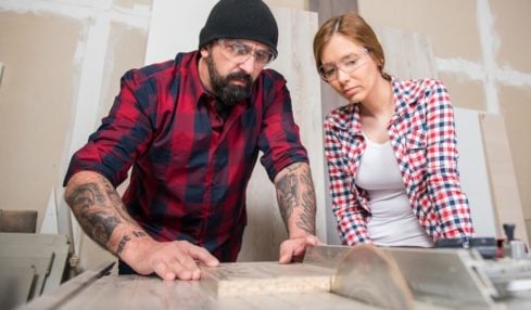 Ausbaufacharbeiter zeigt einer Azubine den Umgang mit dem Schneidewerkzeug in der Ausbildung