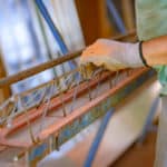 Betonfertigteilbauer in der Ausbildung mit Arbeitshanhdschuhe trägt Gitterträger & Fachwerkträger auf der Baustelle