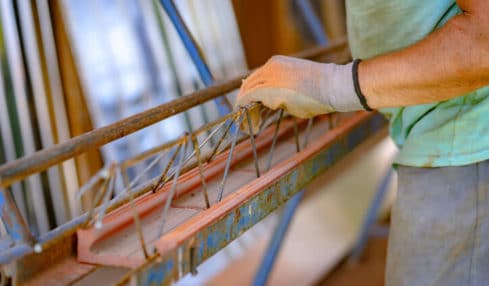 Betonfertigteilbauer in der Ausbildung mit Arbeitshanhdschuhe trägt Gitterträger & Fachwerkträger auf der Baustelle
