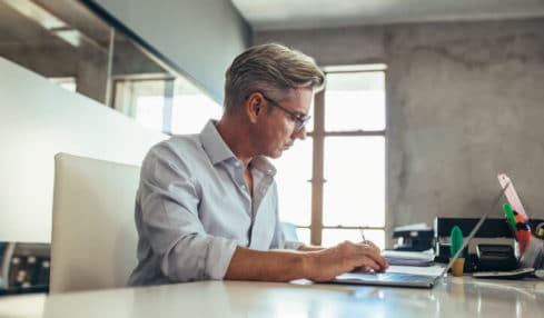 Ein Betriebswirt im Außenhandel arbeitet sitzend am Laptop.