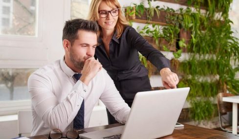 Bankkaufmann Azubi erhält Anweisungen von seiner Chefin vorm Laptop