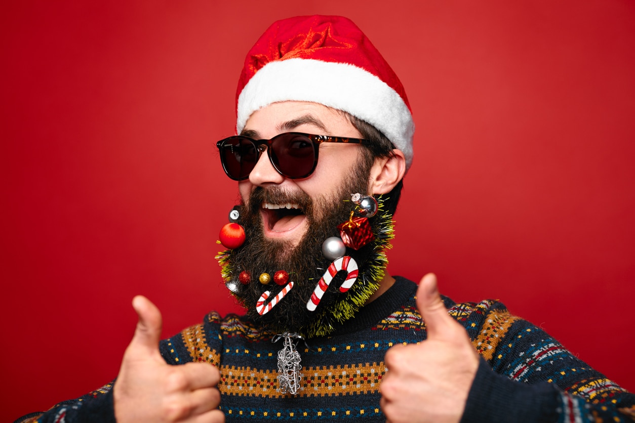 Gut gelaunter Mann mit Nikolausmütze und Sonnenbrille macht thumbs up auf Weihnachtsfeier