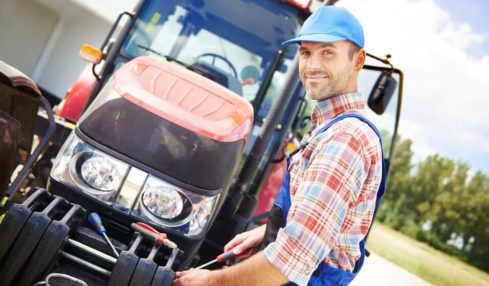 Ein Landmaschinenmechaniker mit blauer Mütze beim Reparieren eines Traktors