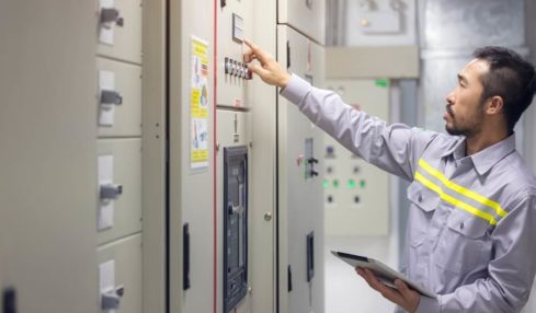 Ein schwarzhaariger Maschinen- und Anlageführer beim Betätigen einer Anlage.