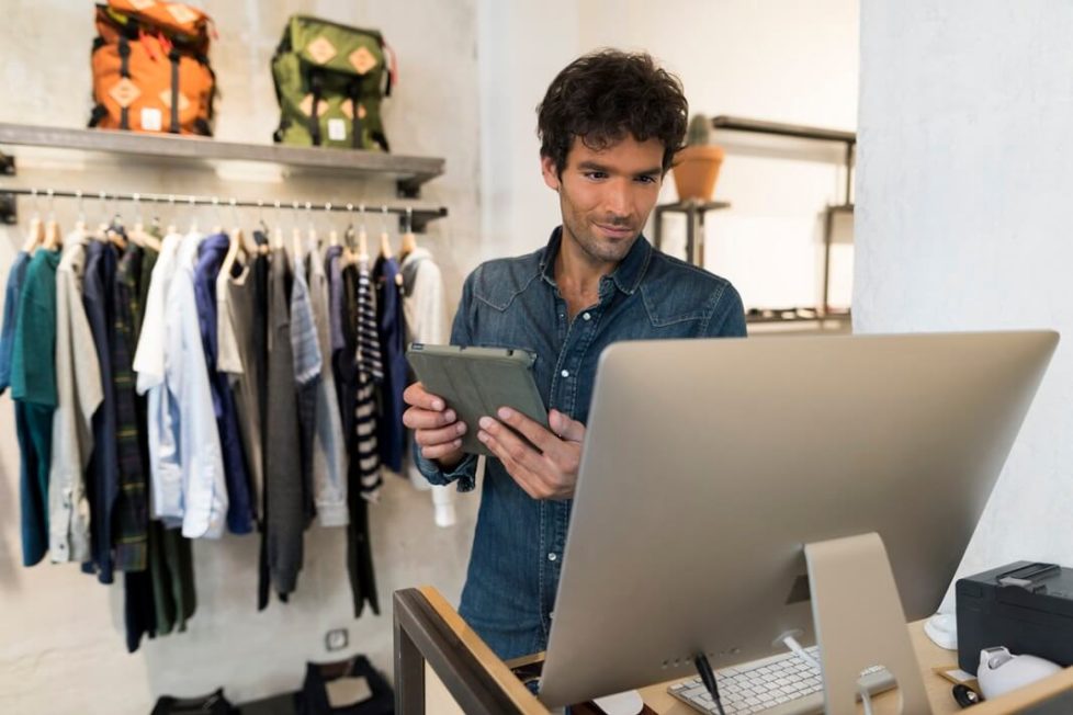 Ein dualer Modemanagement Student vor dem Rechner bei der Arbeit im Mode-Store.
