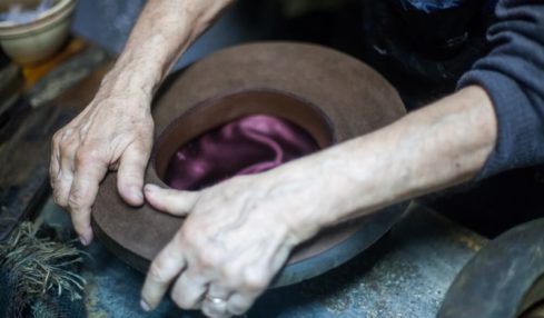 Ein Hut wird per Hand von einem Modisten bearbeitet