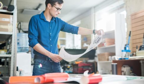 Ein junger Schilder- und Lichtreklamehersteller in der Werkstattwährend der Ausbildung