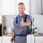 Ein glücklicher Schädlingsbekämpfer zeigt Daumen nach oben in einer Küche