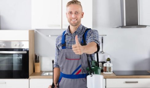 Ein glücklicher Schädlingsbekämpfer zeigt Daumen nach oben in einer Küche