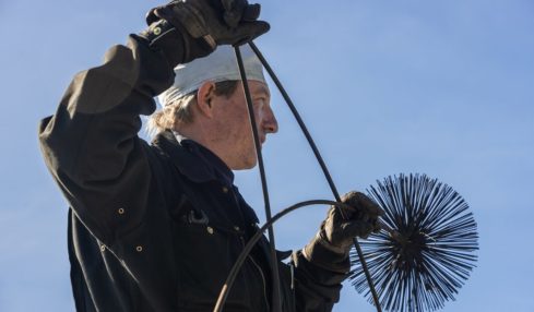 Ein Schornsteinfeger mit einem Kamimbesen in den Händen