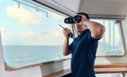 Ein angehender Nautischer Offiziersass mit Fernglas & Walkie-Talkie während der Ausbildung auf dem Schiff