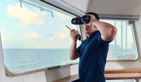 Ein angehender Nautischer Offiziersass mit Fernglas & Walkie-Talkie während der Ausbildung auf dem Schiff