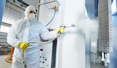 Ein Azubi im Schutzanzug bei der Metall-Beschichtung in der Oberflächenbeschichter Ausbildung