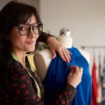 Eine dunkelhaarige Frau mit Brille im Attelier in der Textilgestalter Ausbildung