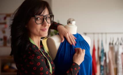 Eine dunkelhaarige Frau mit Brille im Attelier in der Textilgestalter Ausbildung