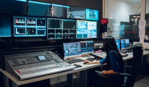 Eine Mediengestalterin für Bild und Ton sitzt an ihrem Arbeitsplatz während ihrer Ausbildung