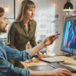 Mediengestalter zeigt einer Kollegin etwas am PC während der Mediengestalter Digital und Print Ausbildung
