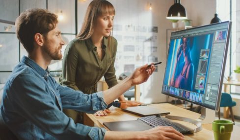 Mediengestalter zeigt einer Kollegin etwas am PC während der Mediengestalter Digital und Print Ausbildung