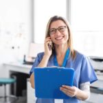 Eine lächelnde angehende Medizinische Fachangestellte am Telefon während der Ausbildung
