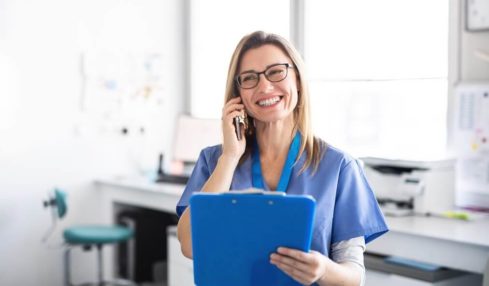 Eine lächelnde angehende Medizinische Fachangestellte am Telefon während der Ausbildung