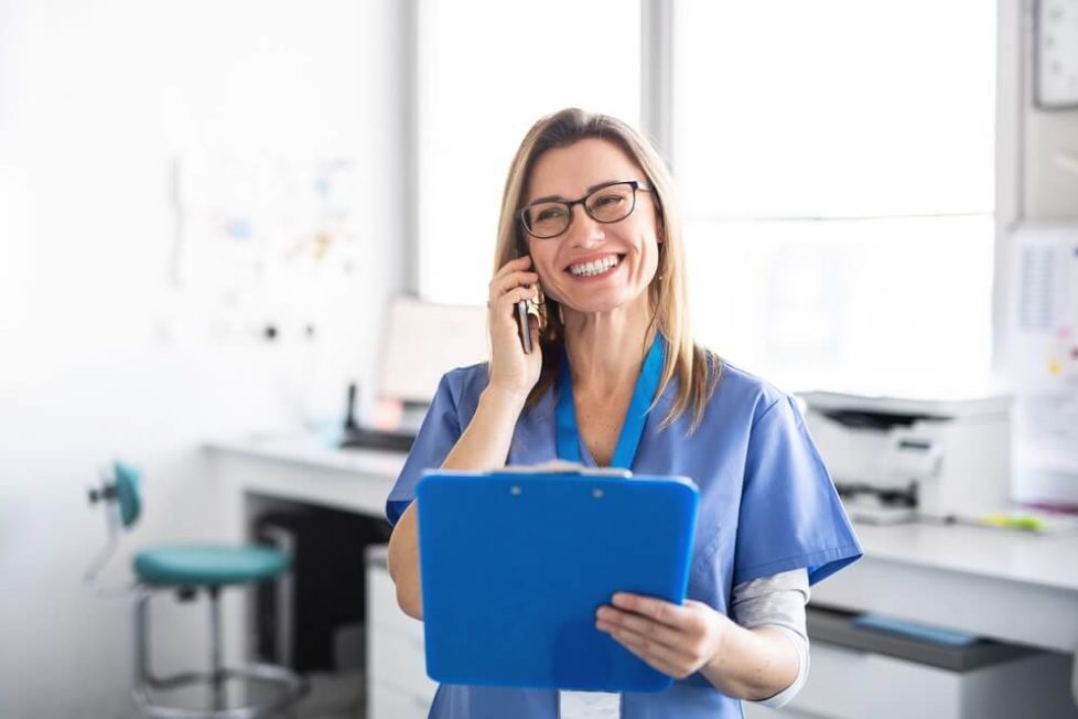 Eine lächelnde angehende Medizinische Fachangestellte am Telefon während der Ausbildung