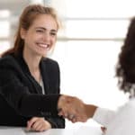 Eine lächelnde angehende Personaldienstleistungskauffrau in der Ausbildung bei einem Interview-Gespräch mit einer Bewerberin