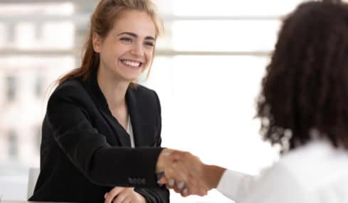 Eine lächelnde angehende Personaldienstleistungskauffrau in der Ausbildung bei einem Interview-Gespräch mit einer Bewerberin