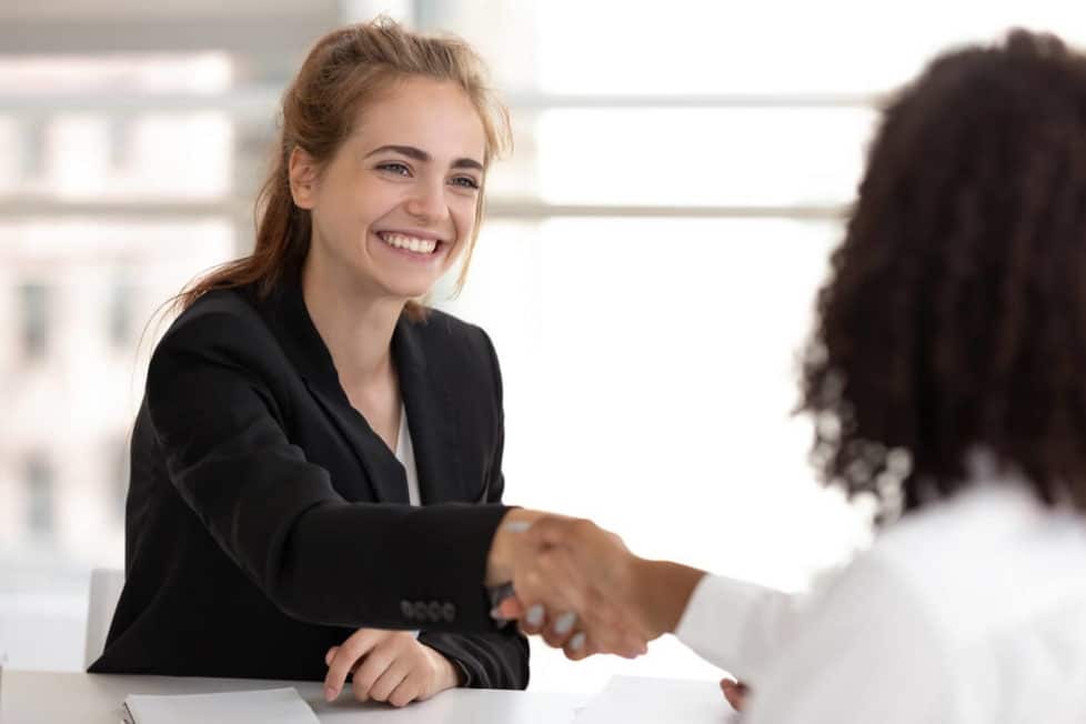 Eine lächelnde angehende Personaldienstleistungskauffrau in der Ausbildung bei einem Interview-Gespräch mit einer Bewerberin