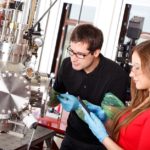 Zwei angehende Physiklaboranten während der Ausbildung mit Laser-Beschichtungskammer