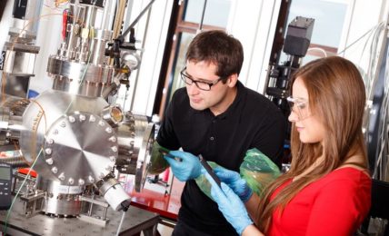 Zwei angehende Physiklaboranten während der Ausbildung mit Laser-Beschichtungskammer
