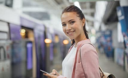 Junge Frau mit Smartphone in der Hand im U-Bahnhof