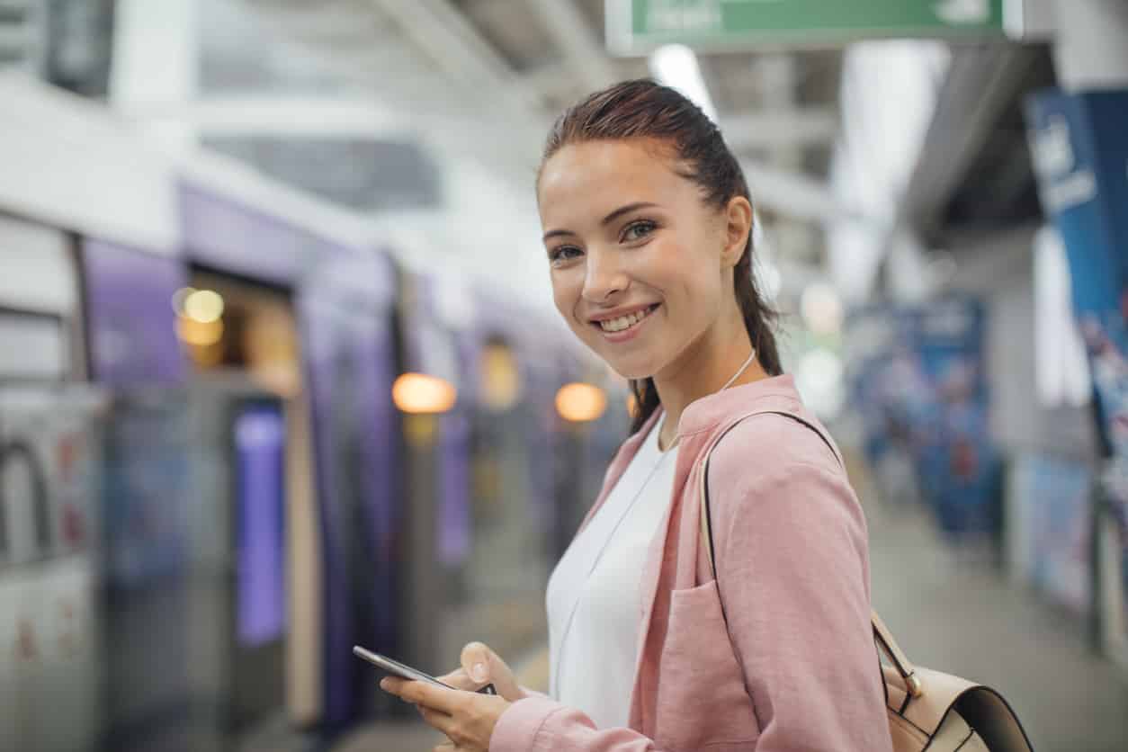 Junge Frau mit Smartphone in der Hand im U-Bahnhof