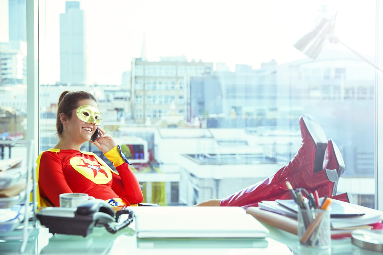 Superwoman im Büro telefonierend am Schreibtisch