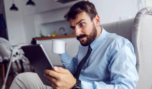 Mann liest verwundert Stellenanzeige auf Tablet