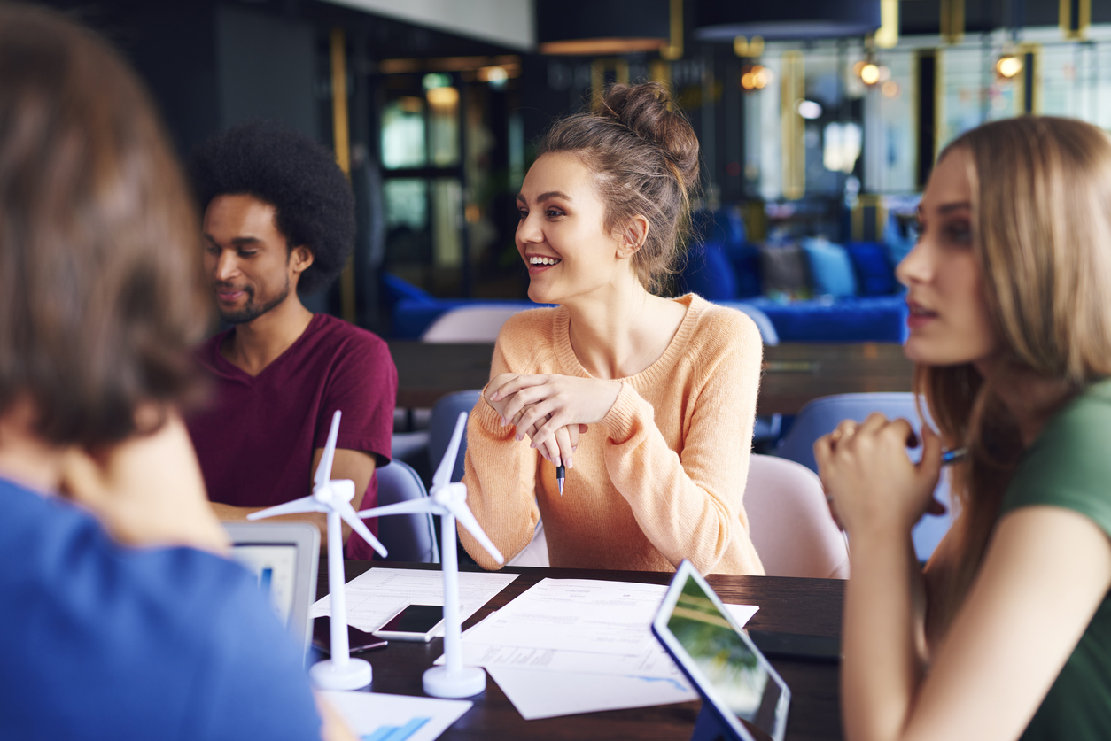 Junge Mitarbeiter im Büro am Besprechungstisch mit Windrädermodellen