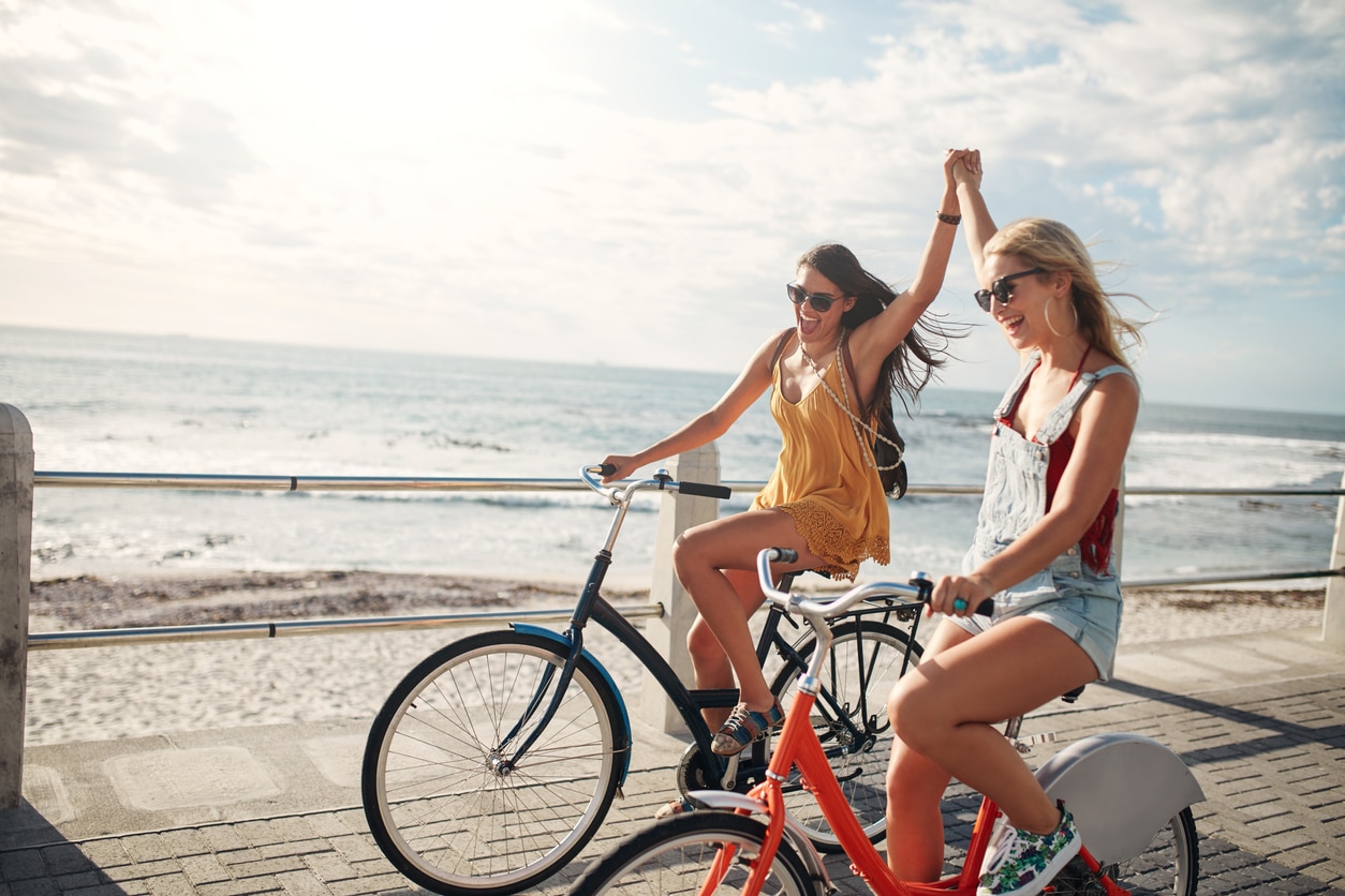 Zwei Freundinnen fahren im Sommer Fahrrad am Strand