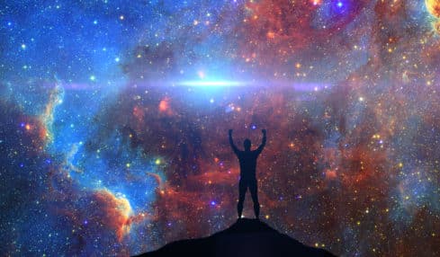 Karriere-Horoskop 2023 Mann steht vor buntem nächtlichen Sternenhimmel