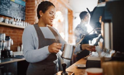 Junge Frau hinter der Theke macht Barista Ausbildung