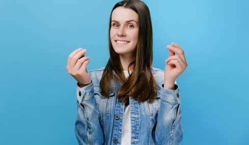 Junge Frau macht mit Fingern Symbolgeste für Geld - Mindestlohn