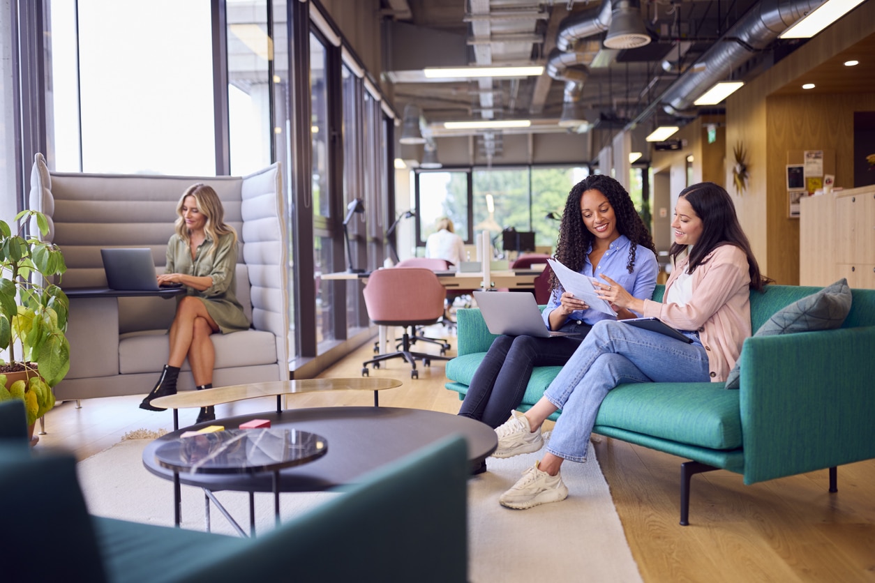 Junge Frauen arbeiten in modernem Großraumbüro mit New Work Charakter