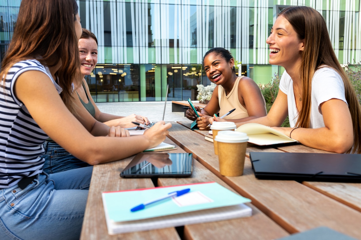 Studenten am Tisch unterhalten sich fröhlich im Freien - Regelstudienzeit